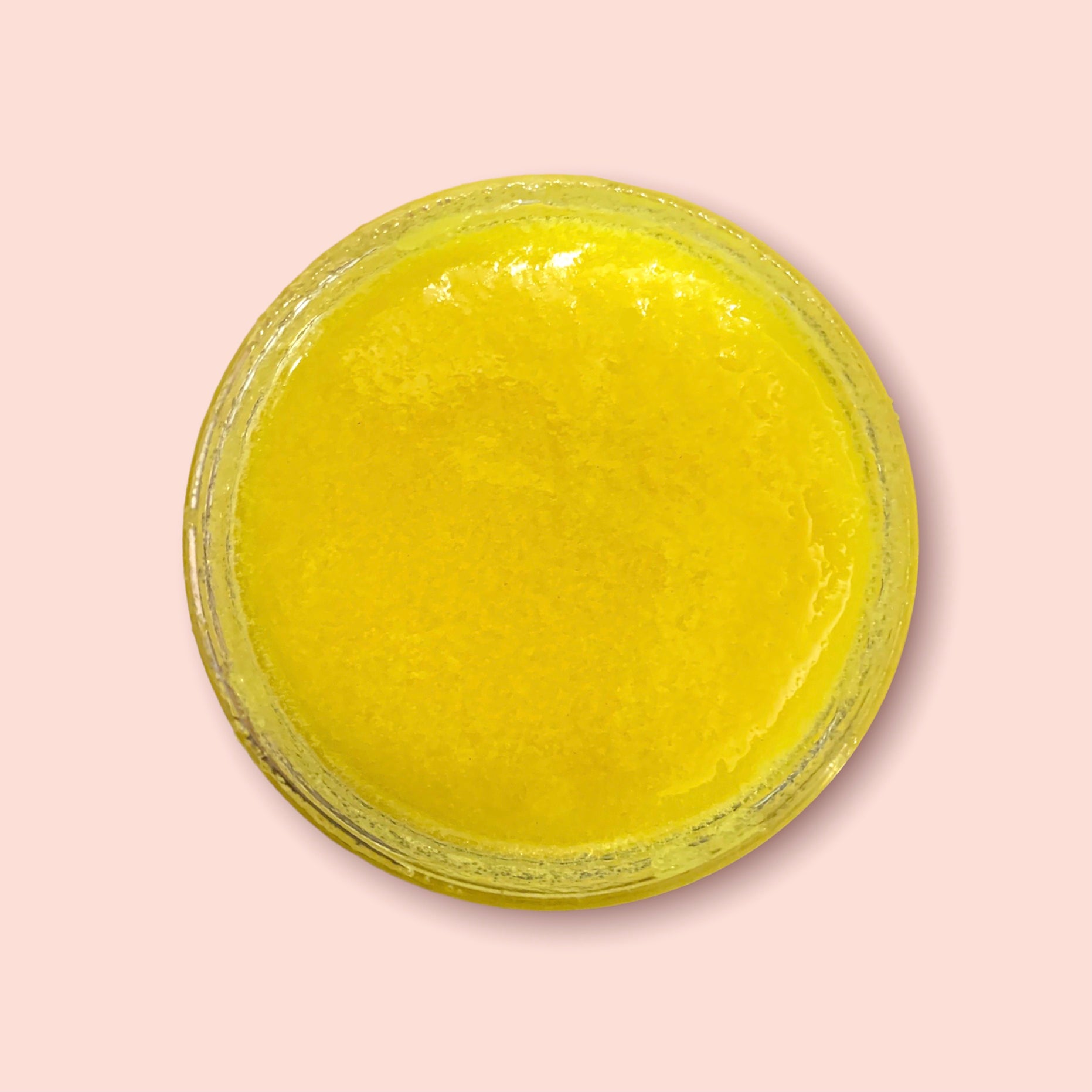 a top view of inside of a jar of yellow turmeric exfoliating sugar scrub